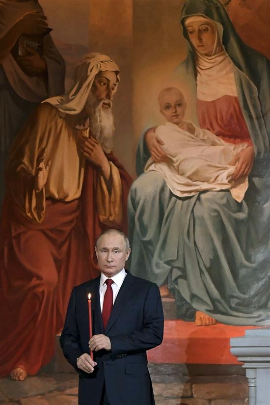 当地时间2021年5月2日，俄罗斯莫斯科，俄罗斯总统普京手持蜡烛、背靠圣母像，在教堂参加东正教复活节仪式。